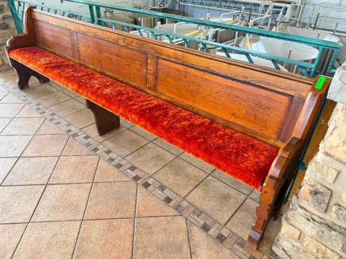 128" ANTIQUE EXTRA-LONG SOLID WOOD BENCH WITH HIGH PANELED BACK, DECORATIVE CARVED END SUPPORTS, AND RED UPHOLSTERED SEAT. HEAVY WOOD CONSTRUCTION WITH DARK STAINED FINISH