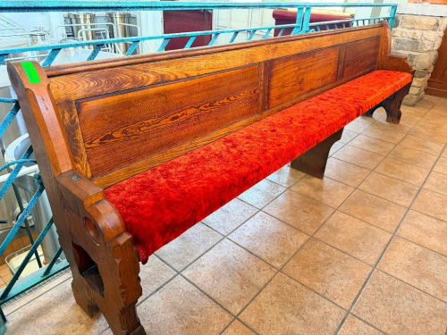 128" ANTIQUE EXTRA-LONG SOLID WOOD BENCH WITH HIGH PANELED BACK, DECORATIVE CARVED END SUPPORTS, AND RED UPHOLSTERED SEAT. HEAVY WOOD CONSTRUCTION WITH DARK STAINED FINISH