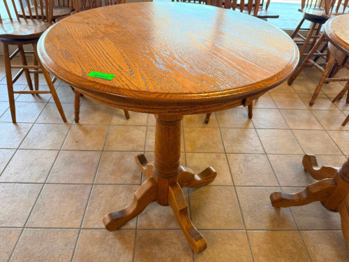36" ROUND OAK PEDESTAL TABLE WITH WOOD-GRAIN FINISH, MOLDED EDGE, SINGLE TURNED CENTER PEDESTAL, AND FOUR-FOOT BASE.