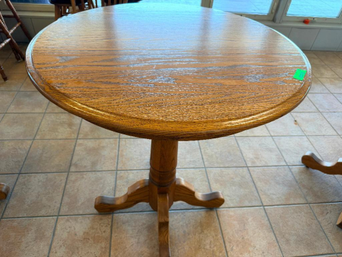 36" ROUND OAK PEDESTAL TABLE WITH WOOD-GRAIN FINISH, MOLDED EDGE, SINGLE TURNED CENTER PEDESTAL, AND FOUR-FOOT BASE.