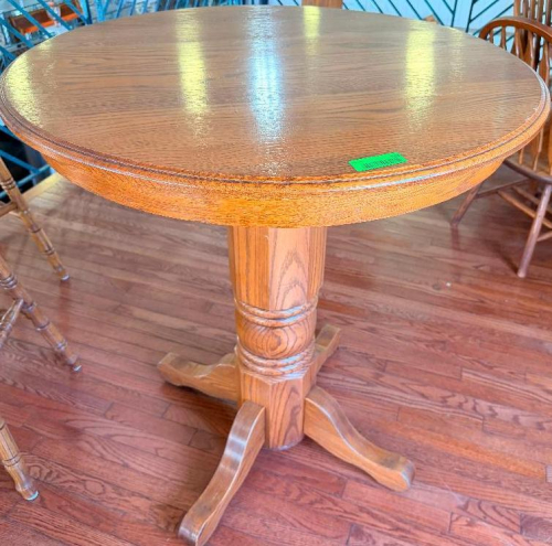 36" ROUND OAK PEDESTAL TABLE WITH WOOD-GRAIN FINISH, MOLDED EDGE, SINGLE TURNED CENTER PEDESTAL, AND FOUR-FOOT BASE.