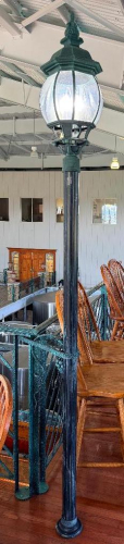 DECORATIVE FREESTANDING LAMP POST WITH BLACK FLUTED COLUMN, ORNATE LANTERN-STYLE FIXTURE, CLEAR TEXTURED GLASS PANELS, AND MULTIPLE CANDELABRA-STYLE LIGHTS.