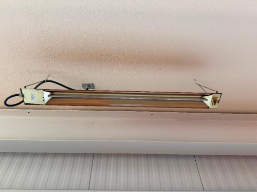 (2) CEILING-SUSPENDED ELECTRIC INFRARED RADIANT HEATER WITH LONG RECTANGULAR METAL HOUSING, TWIN HEATING ELEMENTS, AND CHAIN-MOUNT SUSPENSION.