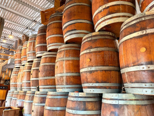 DECORATIVE WALL DISPLAY CONSTRUCTED WITH MULTIPLE WOODEN BARRELS AND BARREL SECTIONS WITH METAL HOOPS, ARRANGED AND MOUNTED ACROSS WALL SURFACE.