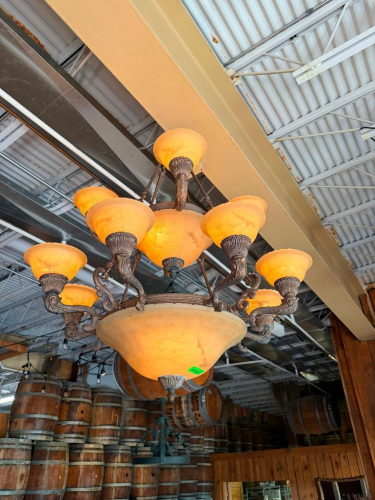 ORNATE MULTI-LIGHT CHANDELIER WITH DECORATIVE METAL FRAME, SCROLLED ARMS, AMBER ALABASTER-STYLE GLASS SHADES, LARGE CENTER BOWL, AND TWO-TIER LIGHT CONFIGURATION.