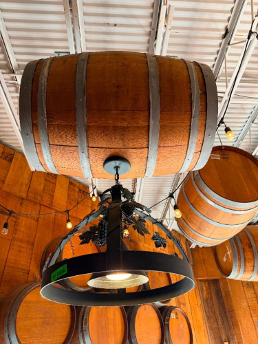 DECORATIVE HANGING WOODEN BARREL LIGHT FIXTURE WITH METAL HOOPS, CIRCULAR METAL LIGHT FRAME, AND DECORATIVE GRAPE VINE, LEAF, AND GRAPE CLUSTER ACCENTS. 20" SHADE.