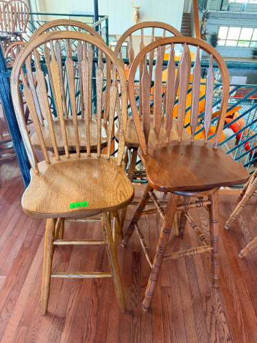 (4) 30" WOOD WINDSOR-STYLE BAR HEIGHT CHAIRS WITH HIGH SPINDLE BACKS, CONTOURED WOOD SEATS, TURNED LEGS AND FOOTREST STRETCHERS. MIXED OAK-TONE WOOD FINISHES.