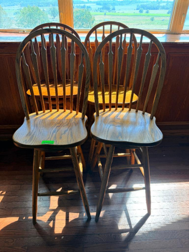 (4) 30" WOOD WINDSOR-STYLE BAR HEIGHT CHAIRS WITH HIGH SPINDLE BACKS, CONTOURED WOOD SEATS, TURNED LEGS AND FOOTREST STRETCHERS. MIXED OAK-TONE WOOD FINISHES.