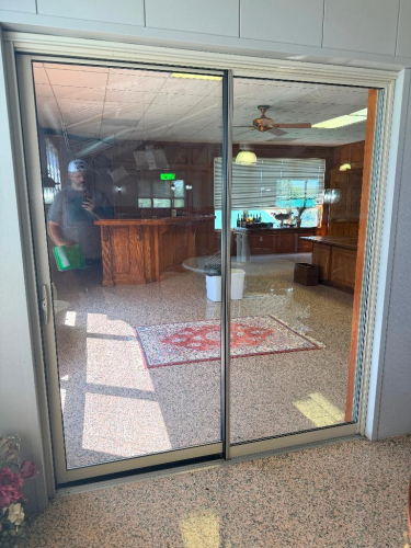 ALUMINUM-FRAMED TWO-PANEL SLIDING GLASS DOOR ASSEMBLY WITH CLEAR GLASS PANELS, TRACK FRAME AND RECESSED HANDLE.