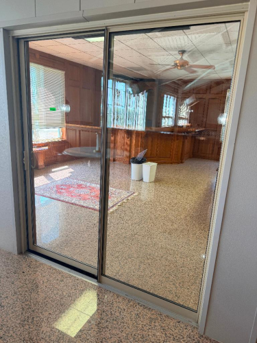 ALUMINUM-FRAMED TWO-PANEL SLIDING GLASS DOOR ASSEMBLY WITH CLEAR GLASS PANELS, TRACK FRAME AND RECESSED HANDLE.