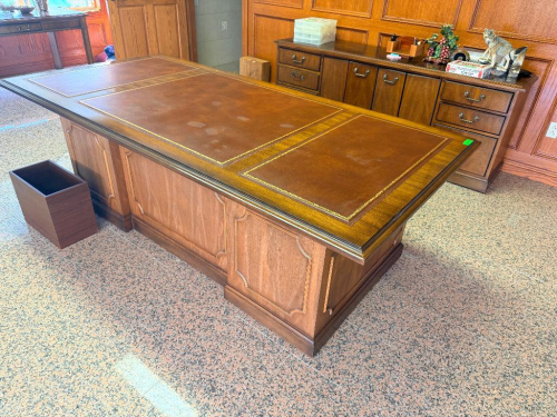 LARGE EXECUTIVE PARTNER DESK WITH WOOD CONSTRUCTION, THREE-PANEL BROWN LEATHER WRITING SURFACE WITH GOLD-TOOLED BORDER, DECORATIVE PANEL SIDES, BRASS-TONE HARDWARE AND MULTIPLE DRAWERS ON BOTH SIDES.