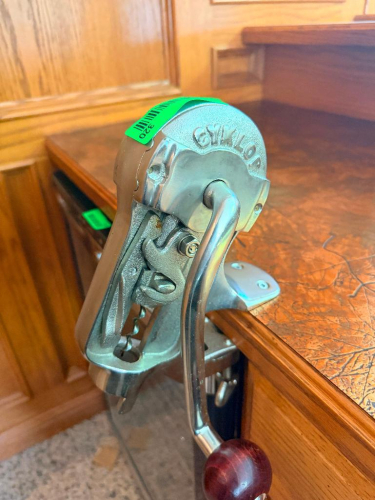 GYKLOP HEAVY-DUTY MANUAL BENCH-MOUNTED WINE BOTTLE CORKER WITH CAST METAL FRAME, LONG LEVER HANDLE, ADJUSTABLE BOTTLE PLATFORM, CORK COMPRESSION MECHANISM, AND COUNTER CLAMP.