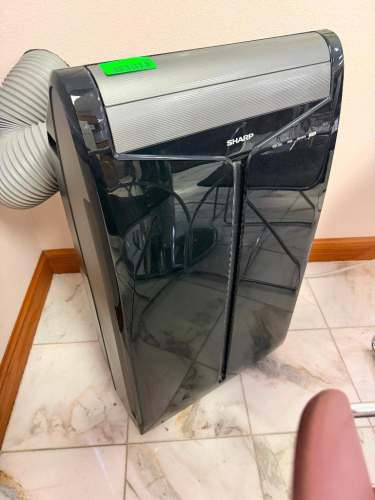 SHARP PORTABLE AIR CONDITIONER WITH EXHAUST HOSE, DIGITAL CONTROLS AND BLACK CABINET.