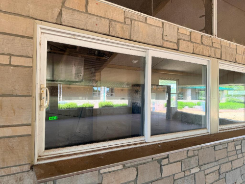(3) COMMERCIAL SLIDING WINDOWS WITH WHITE METAL FRAMES, CLEAR GLASS PANELS AND INTEGRATED SLIDING TRACKS.