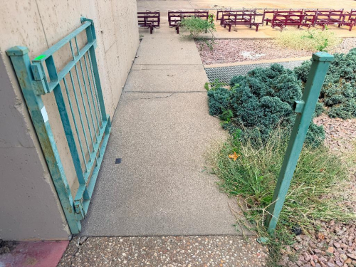 CUSTOM POWDER-COATED METAL SWING GATE WITH VERTICAL BAR DESIGN, SQUARE TUBE FRAME, HINGES AND SUPPORT POST.