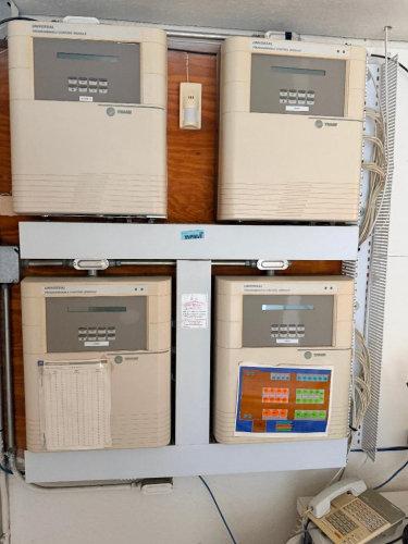 (4) TRANE UNIVERSAL PROGRAMMABLE CONTROL MODULES WITH DIGITAL LCD DISPLAYS AND KEYPAD CONTROLS, MOUNTED WITH ASSOCIATED WIRING, WIRE MANAGEMENT, AND SUPPORT FRAME.