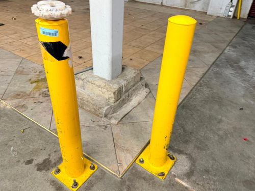 (4) HEAVY-DUTY STEEL SAFETY BOLLARDS WITH ROUND TUBULAR CONSTRUCTION AND WELDED SQUARE BASE PLATES.