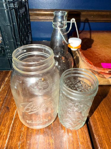(1) MILK CRATE FULL OF SMALL MASON JARS.