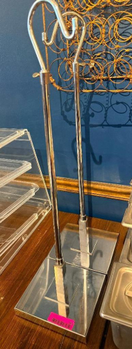 (2) COMMERCIAL CHROME PLATED METAL BAG / PURSE STANDS WITH TALL UPRIGHT POSTS, CURVED DOUBLE-HOOK TOPS, AND HEAVY RECTANGULAR BASES. POLISHED METAL FINISH