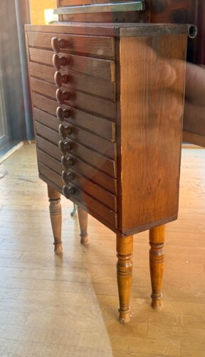 ANTIQUE WOODEN 10-DRAWER SPECIMEN / COLLECTOR&rsquo;S CABINET ON FOUR TURNED WOOD LEGS. FEATURES TEN SHALLOW INDIVIDUAL DRAWERS WITH CENTERED ROUND WOOD PULLS, SOLID WOOD CASE CONSTRUCTION, AND TRADITIONAL JOINERY.