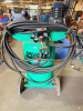 SPEEDAIRE PORTABLE VERTICAL ELECTRIC AIR COMPRESSOR WITH 20-GALLON AIR RECEIVER, OIL-LUBRICATED PUMP, PRESSURE REGULATOR, DUAL PRESSURE GAUGES, WHEELS, HANDLE, AND AIR HOSES.