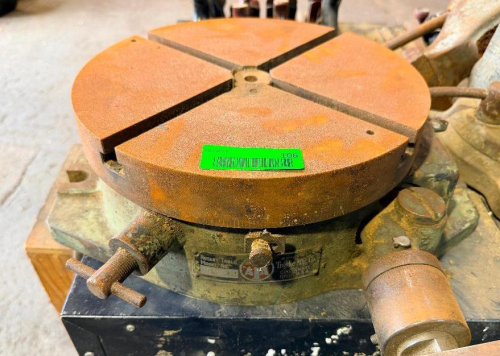 HEAVY-DUTY MANUAL ROTARY TABLE WITH ROUND T-SLOTTED WORK SURFACE, 360-DEGREE GRADUATED SCALE, HAND CRANK DRIVE AND CAST IRON BASE.
