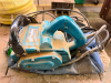 MAKITA ELECTRIC BELT SANDER WITH FRONT AND REAR HANDLES, DUST COLLECTION PORT, AND CORDED ELECTRIC MOTOR.