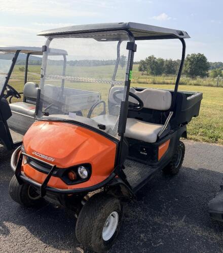 JACOBSEN TRUCKSTER LX GAS POWERED UTILITY VEHICLE WITH TWO-PERSON BENCH SEAT, REAR CARGO BED, WINDSHIELD, CANOPY TOP, FRONT BRUSH GUARD, HEADLIGHTS, TAILLIGHTS, HORN, 12V ACCESSORY OUTLET, DIAMOND-PLATE FLOOR, PARKING BRAKE, AND REAR RECEIVER HITCH.
