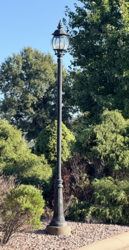 (2) DECORATIVE OUTDOOR LAMP POST WITH BLACK FLUTED POLE, ORNAMENTAL BASE, AND TRADITIONAL LANTERN-STYLE LIGHT FIXTURE WITH CURVED CLEAR GLASS PANELS.