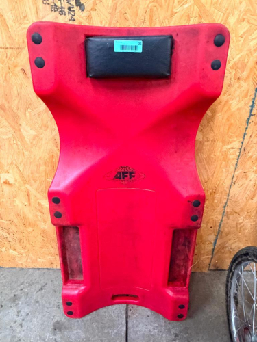 AFF RED AUTOMOTIVE MECHANIC'S CREEPER WITH MOLDED PLASTIC BODY, PADDED HEADREST, RECESSED HAND GRIPS, AND LOW-PROFILE DESIGN.