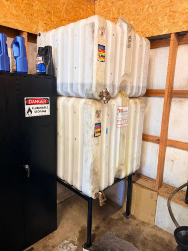(2) RHINO TUFF TANKS POLYETHYLENE BULK FLUID STORAGE TANKS WITH DISPENSING VALVES, STACKED CONFIGURATION AND STEEL SUPPORT STAND.
