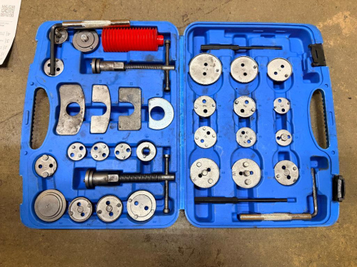 MULTI-PIECE DISC BRAKE CALIPER PISTON WIND BACK TOOL KIT WITH ASSORTED CALIPER ADAPTER PLATES, LEFT AND RIGHT HAND THREADED COMPRESSION TOOLS, REACTION PLATES AND MOLDED PLASTIC CARRYING CASE.