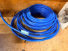 COIL OF BLUE FLEXIBLE PLASTIC TUBING WITH OPEN ENDS.