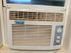 GE WINDOW-MOUNTED AIR CONDITIONER WITH ADJUSTABLE FRONT AIR VENTS, ROTARY TEMPERATURE CONTROL, TWO-SPEED FAN SETTINGS, AND MANUAL POWER SWITCH.