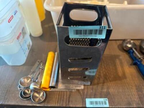 CHEESE GRATER AND ASSORTED MEASURING SPOONS.