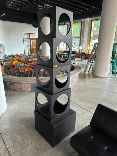 DESCRIPTION 7' MODERN GEOMETRIC LOBBY SCULPTURE WITH FOUR BLACK CUBE STRUCTURES, EACH WITH LARGE CIRCULAR CUTOUTS ON ALL SIDES, MOUNTED ON A MATCHING